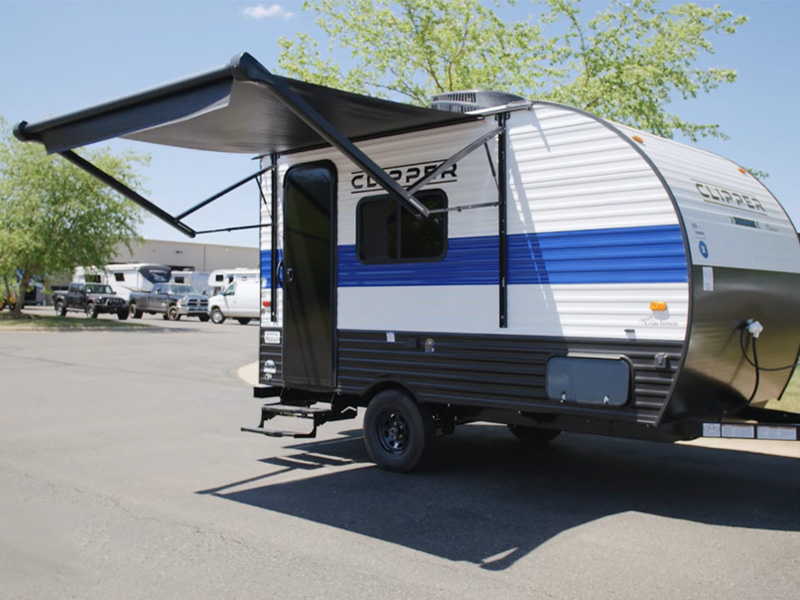 SUV with the awning extended at a shaded campsite